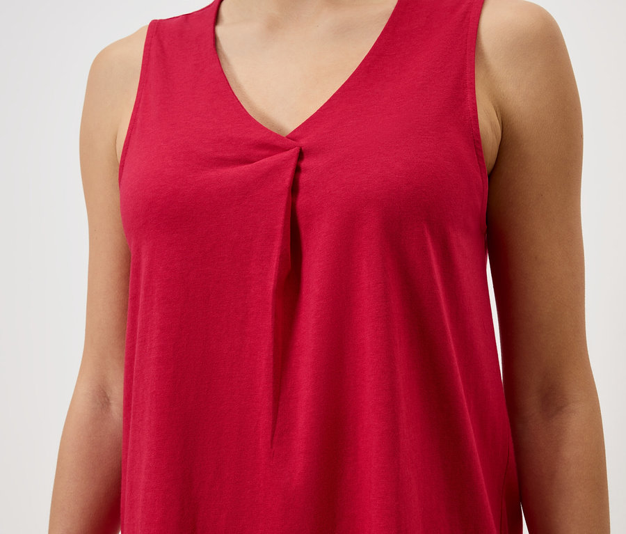 Zbliżenie kobiety ubranej w czerwoną bluzkę bez rękawów z dekoltem w serek.