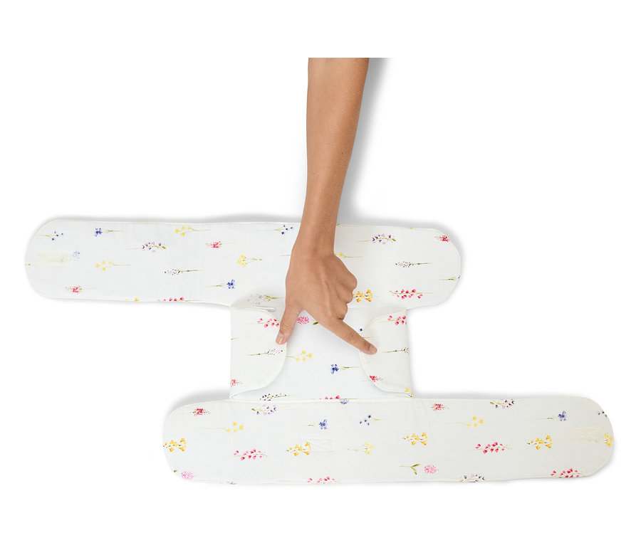Ręka dotyka białej poduszki stabilizującej z kwiatowym wzorem.