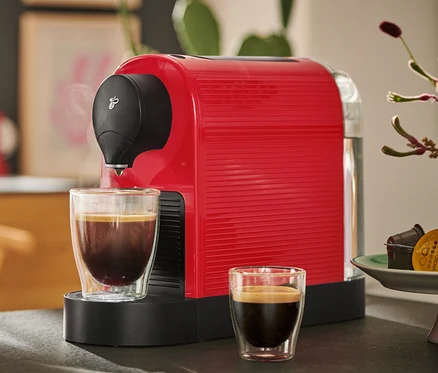 Czerwony ekspres do kawy Cafissimo pure+ z dwiema filiżankami kawy.