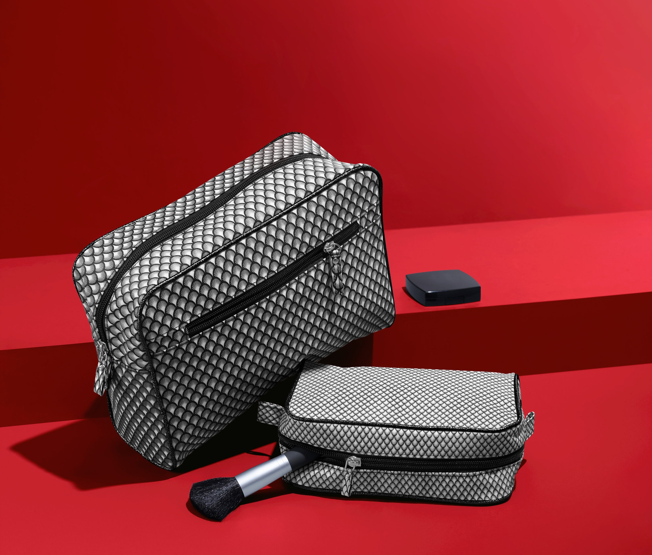 Zestaw kosmetyczek damskich w czarno-biały wzór na czerwonym tle.