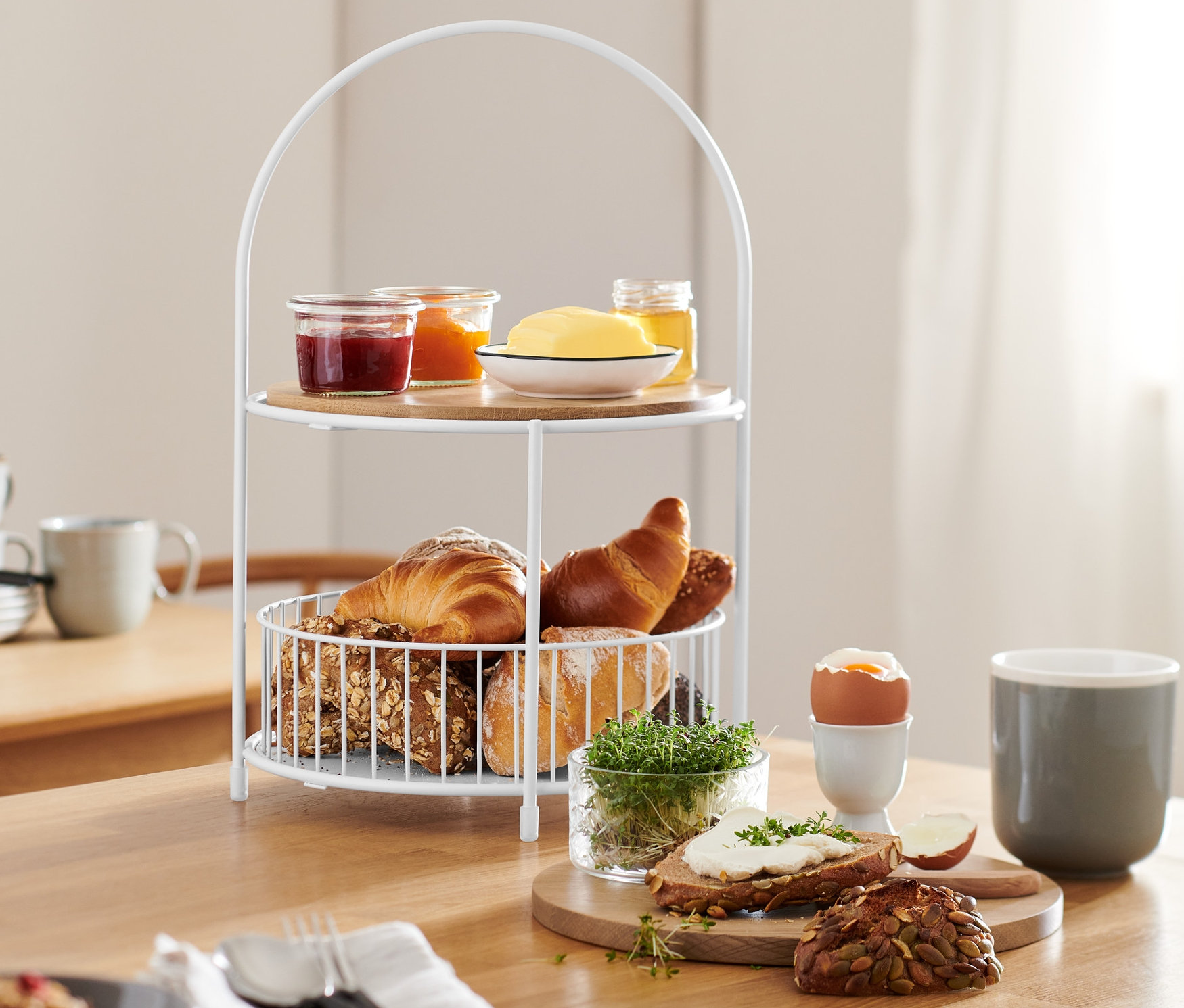 Patera piętrowa z koszykiem na pieczywo na stole z jedzeniem.