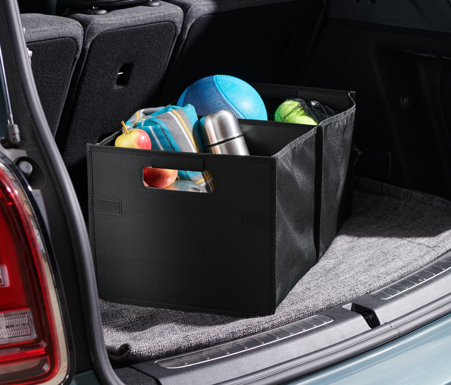 W bagażniku samochodu znajduje się składany organizer do samochodu, w którym przechowywane są różne przedmioty.