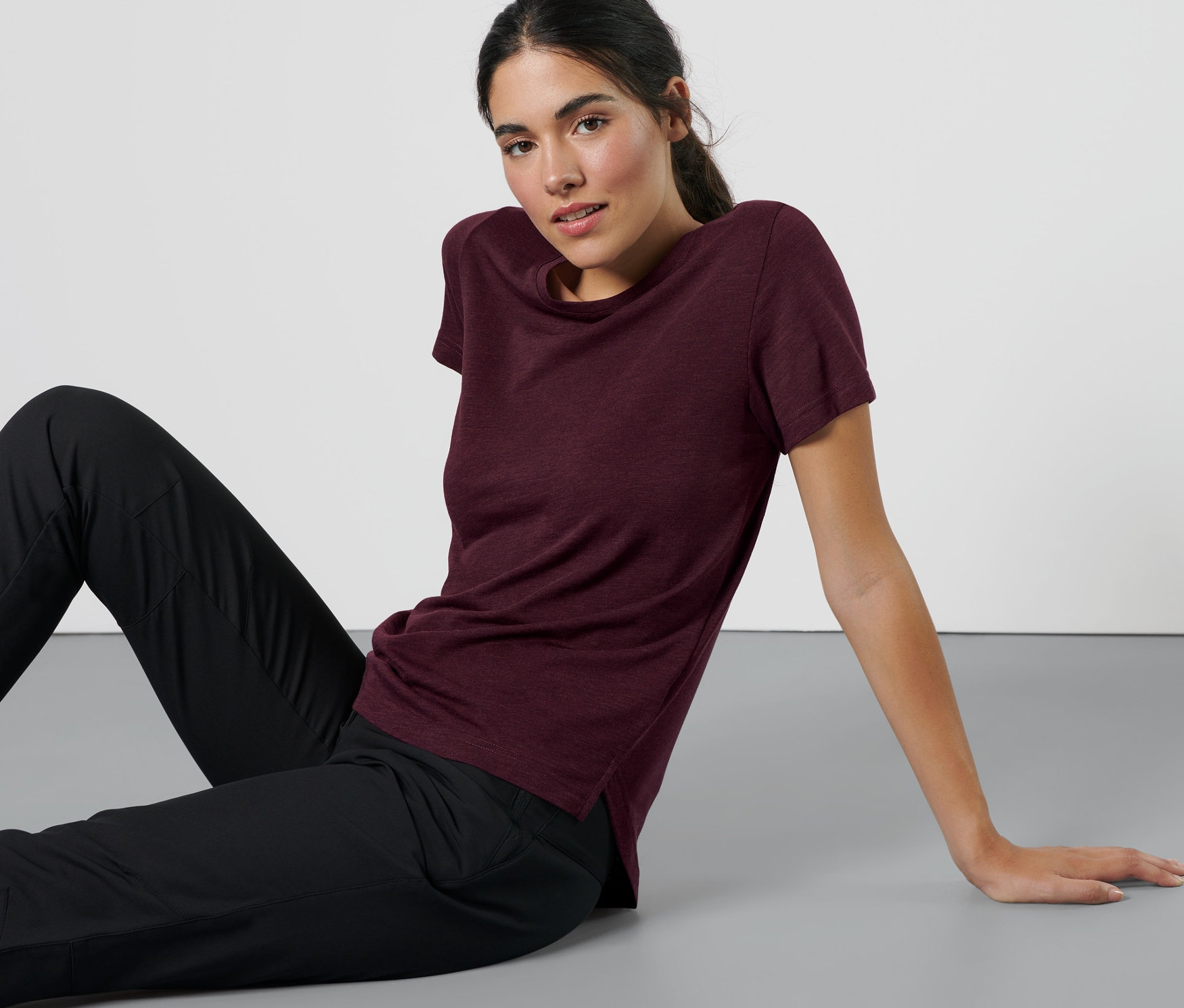 Kobieta siedzi na podłodze w koszulce sportowej.