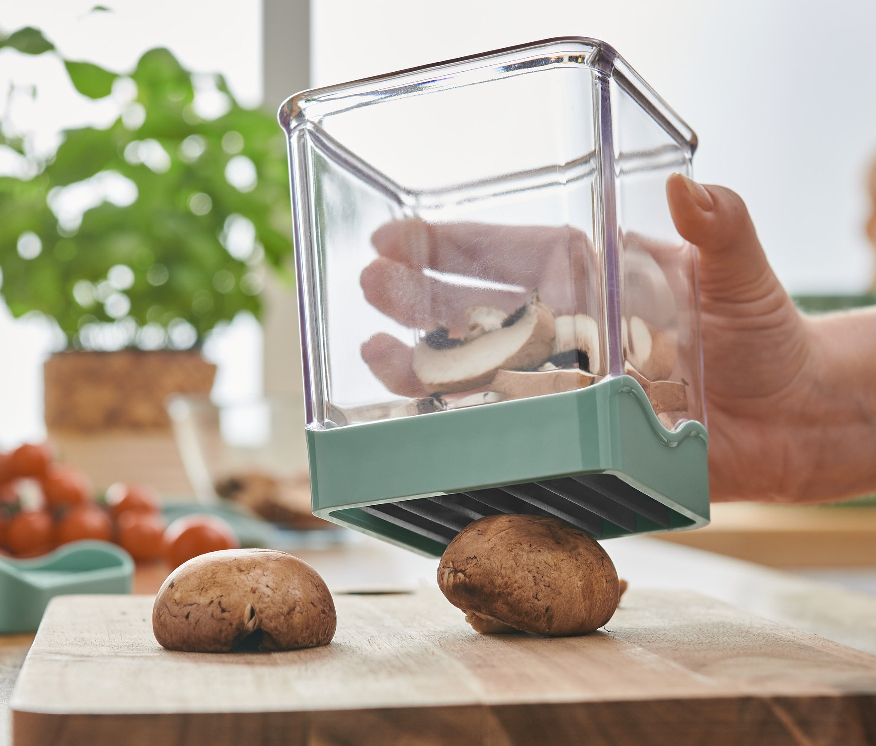 Kobieta kroi pieczarki krajalnicą do owoców i warzyw.