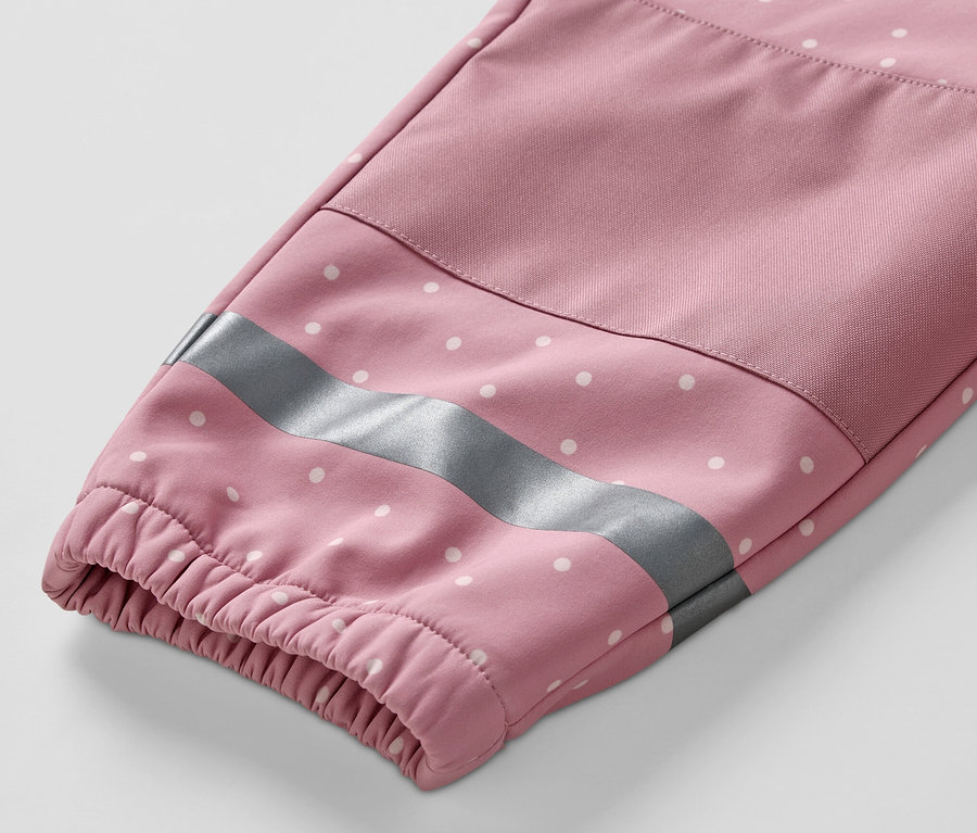 Zbliżenie na rękaw kombinezonu softshellowego dla dzieci w różowe kropki z odblaskowym paskiem.