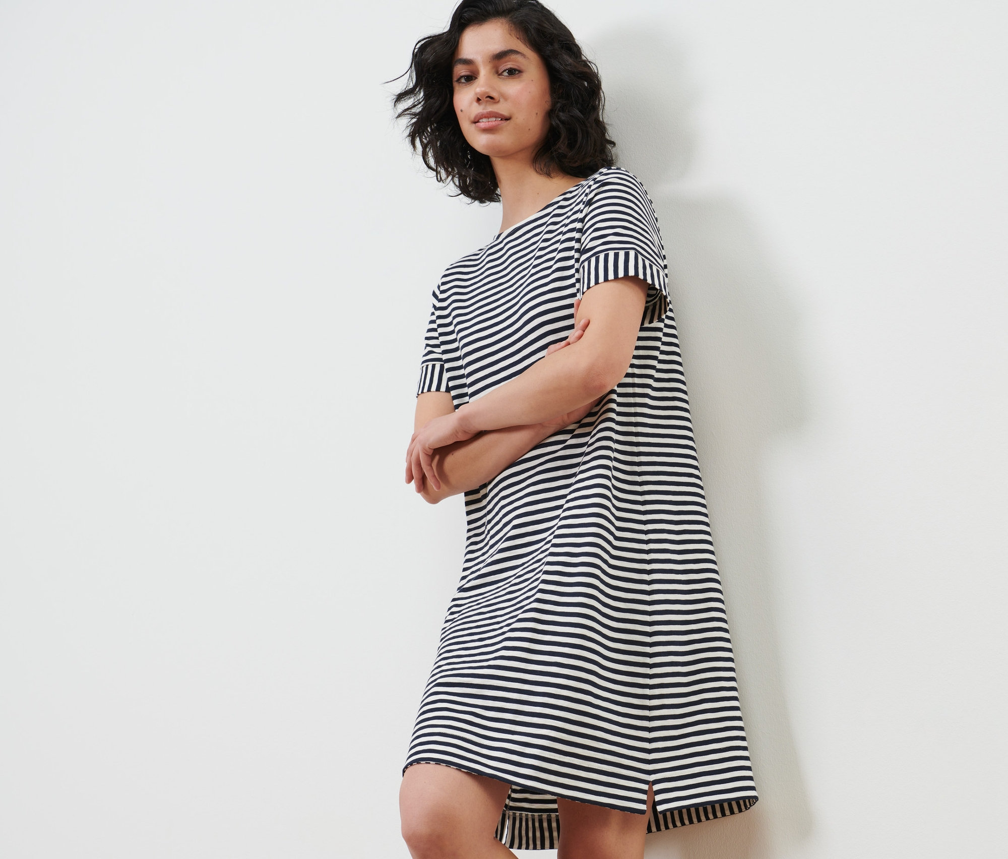 Kobieta pozuje w dżersejowej sukience w paski.