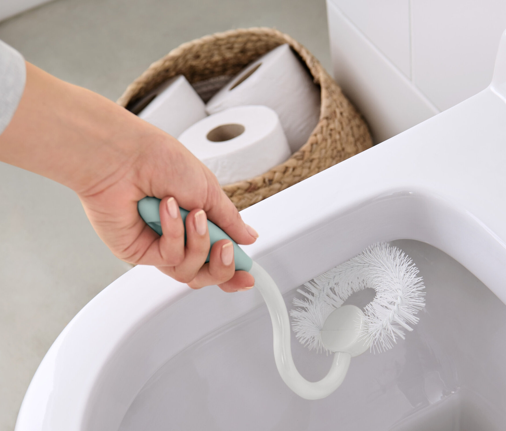 Ręka czyści toaletę szczotką do czyszczenia toalet.