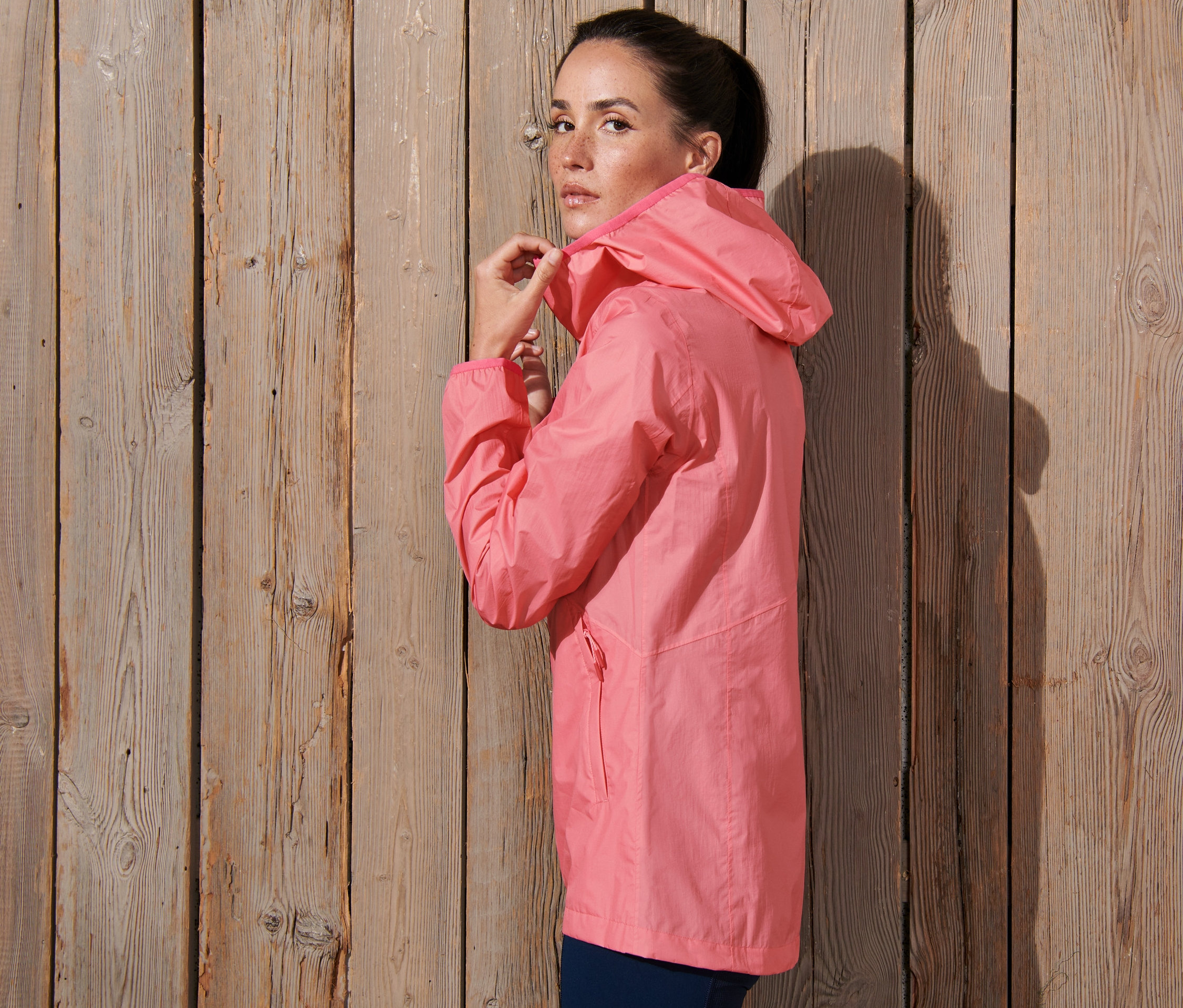 Kobieta zapina różową, pakowaną kurtkę przeciwdeszczową.