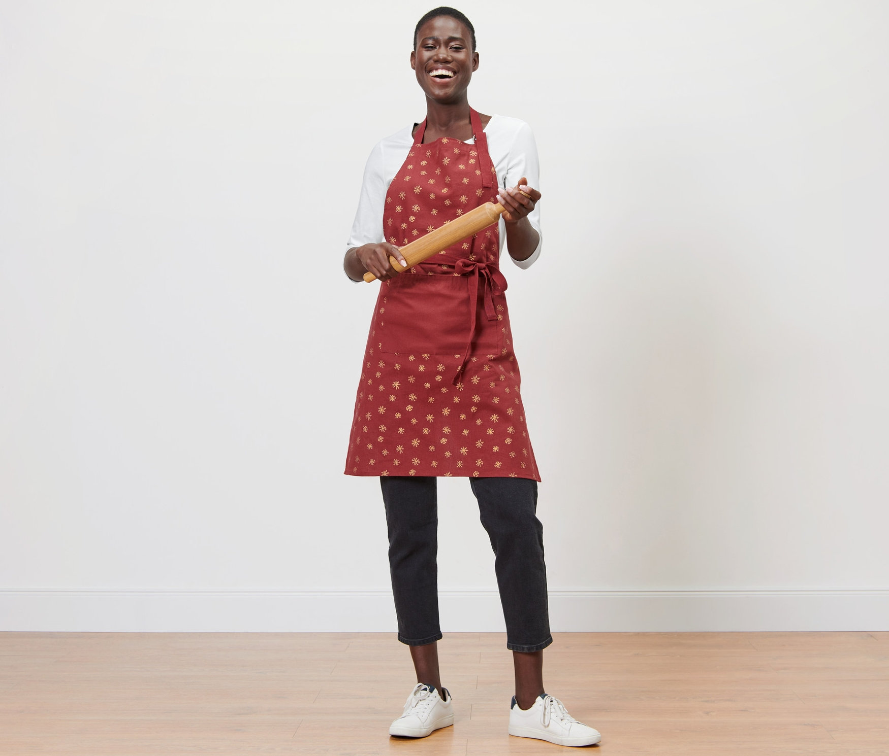 Kobieta trzyma wałek do ciasta i ma na sobie fartuch kuchenny.