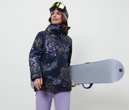 Kobieta trzyma deskę snowboardową i ma na sobie kurtkę narciarską z krótkim zamkiem błyskawicznym.