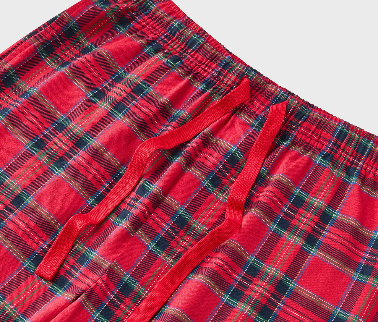 Szczegół czerwonych spodni od piżamy w kratę z czerwonym sznurkiem.