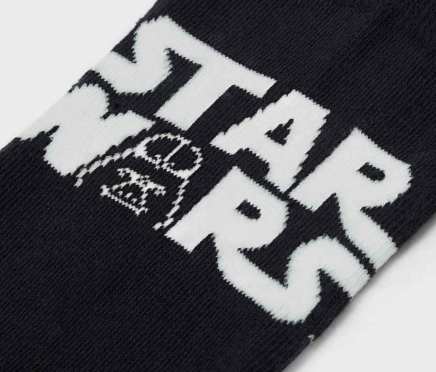 Szczegół czarnej skarpety z białym napisem STAR WARS i ilustracją Dartha Vadera.