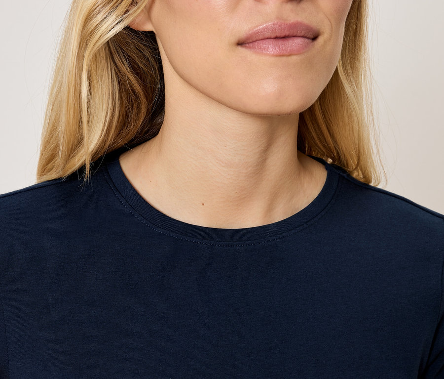 Górna część ciała blondynki w granatowej koszulce.