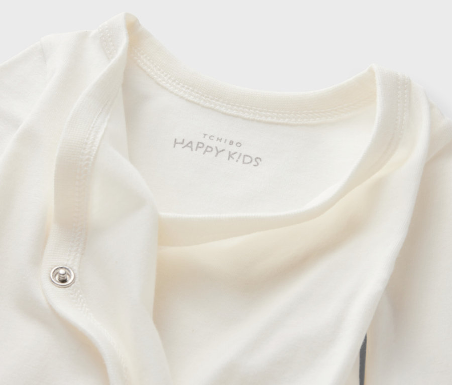 Zbliżenie na białe body niemowlęce rosnące z dzieckiem, 5 par, z logo Tchibo Happy Kids.