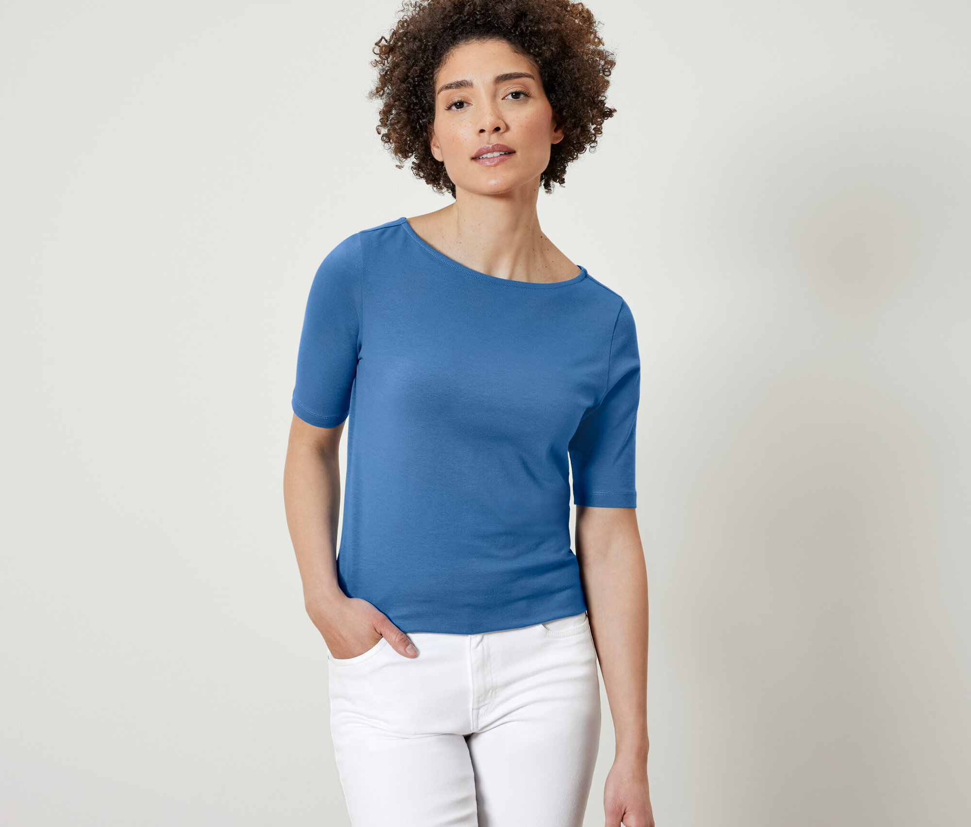 Kobieta pozuje w niebieskiej koszulce z półrękawem.