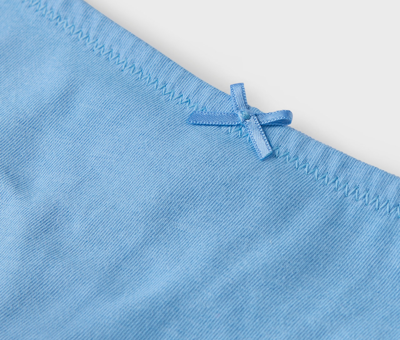 Szczegół jasnoniebieskich majtek z kokardką.