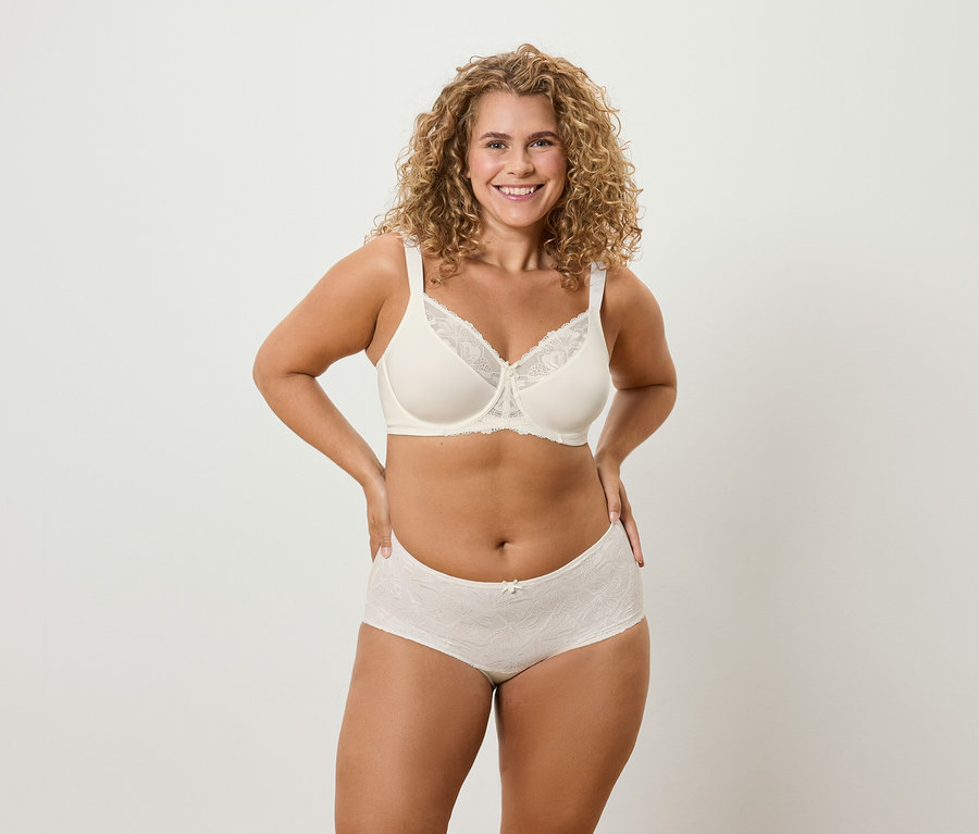 Kobieta z kręconymi włosami pozuje w bieliźnie.