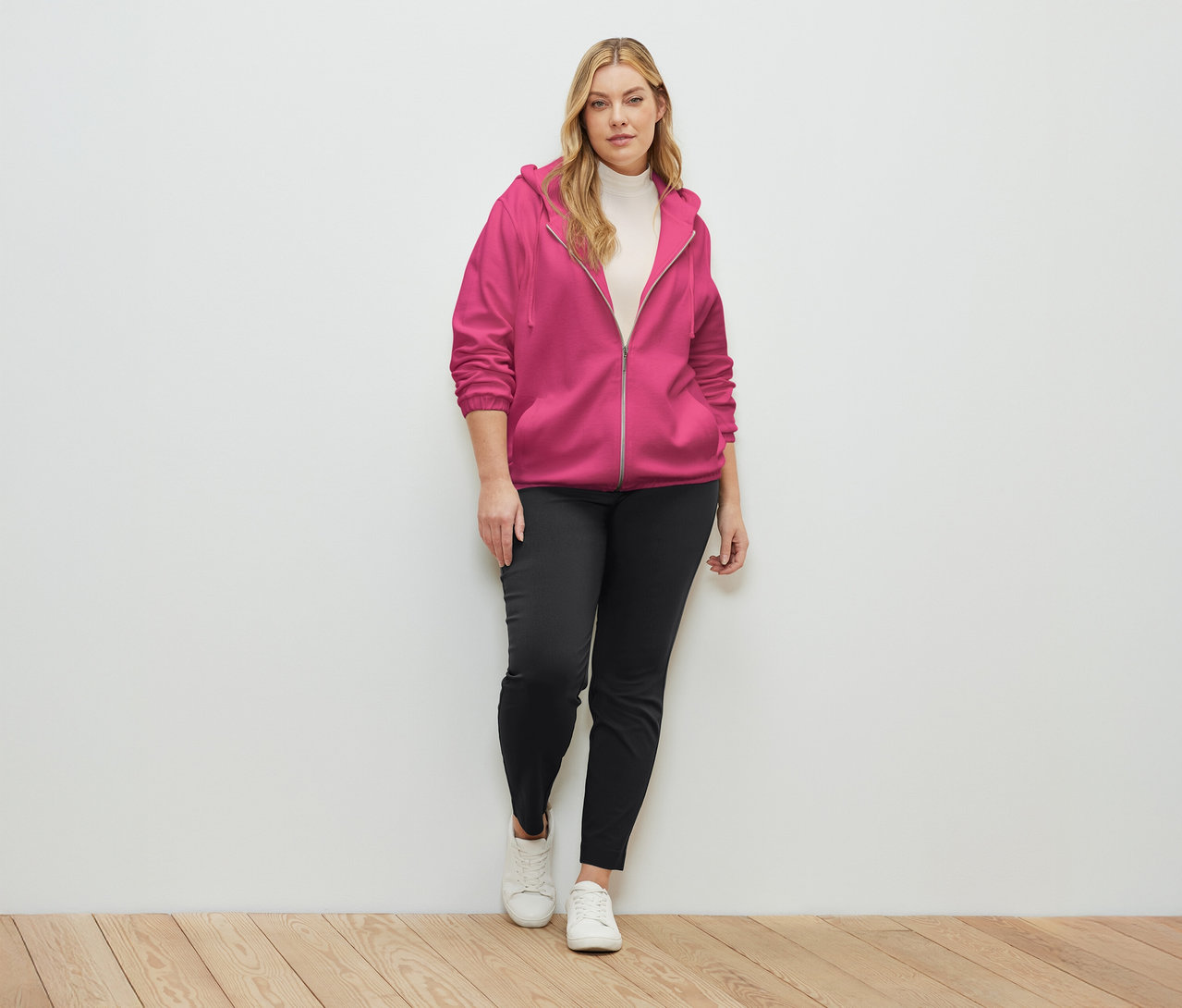 Kobieta ma na sobie rozpinaną bluzę dresową w kolorze fuksji.