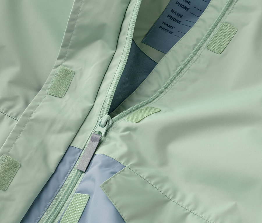 Zbliżenie rozpiętej miętowo-zielonej kurtki z zamkiem błyskawicznym i jasnoniebieskimi akcentami.