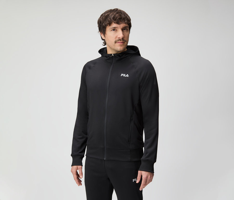 Mężczyzna z wąsami ma na sobie czarny dres Fila z kapturem.