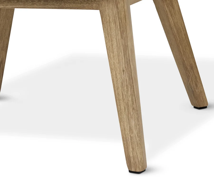 Zbliżenie na drewniane nogi designerskiego fotela z plecionki z podnóżkiem.