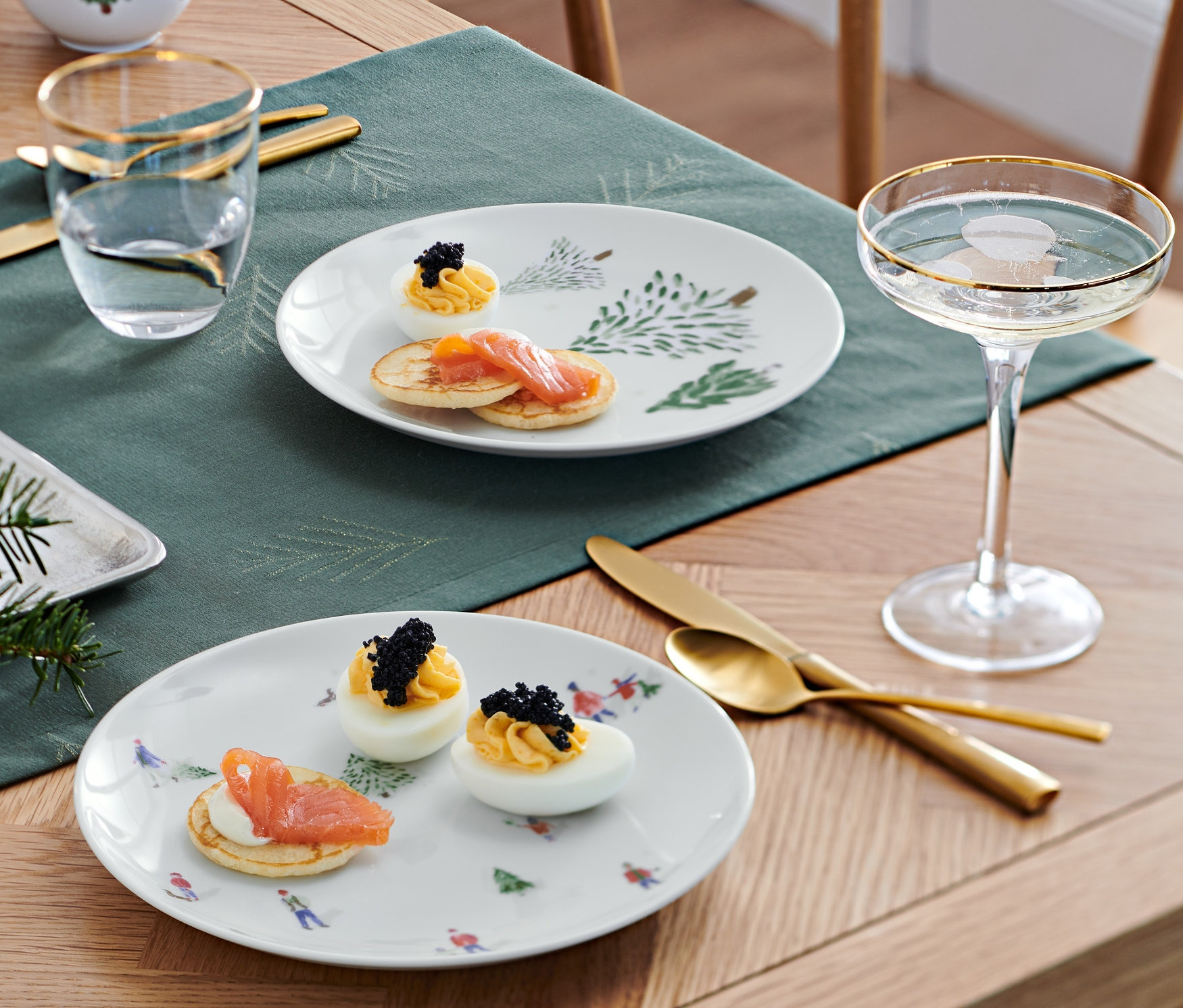 Dwa talerze z przekąskami na drewnianym stole z dekoracjami świątecznymi.