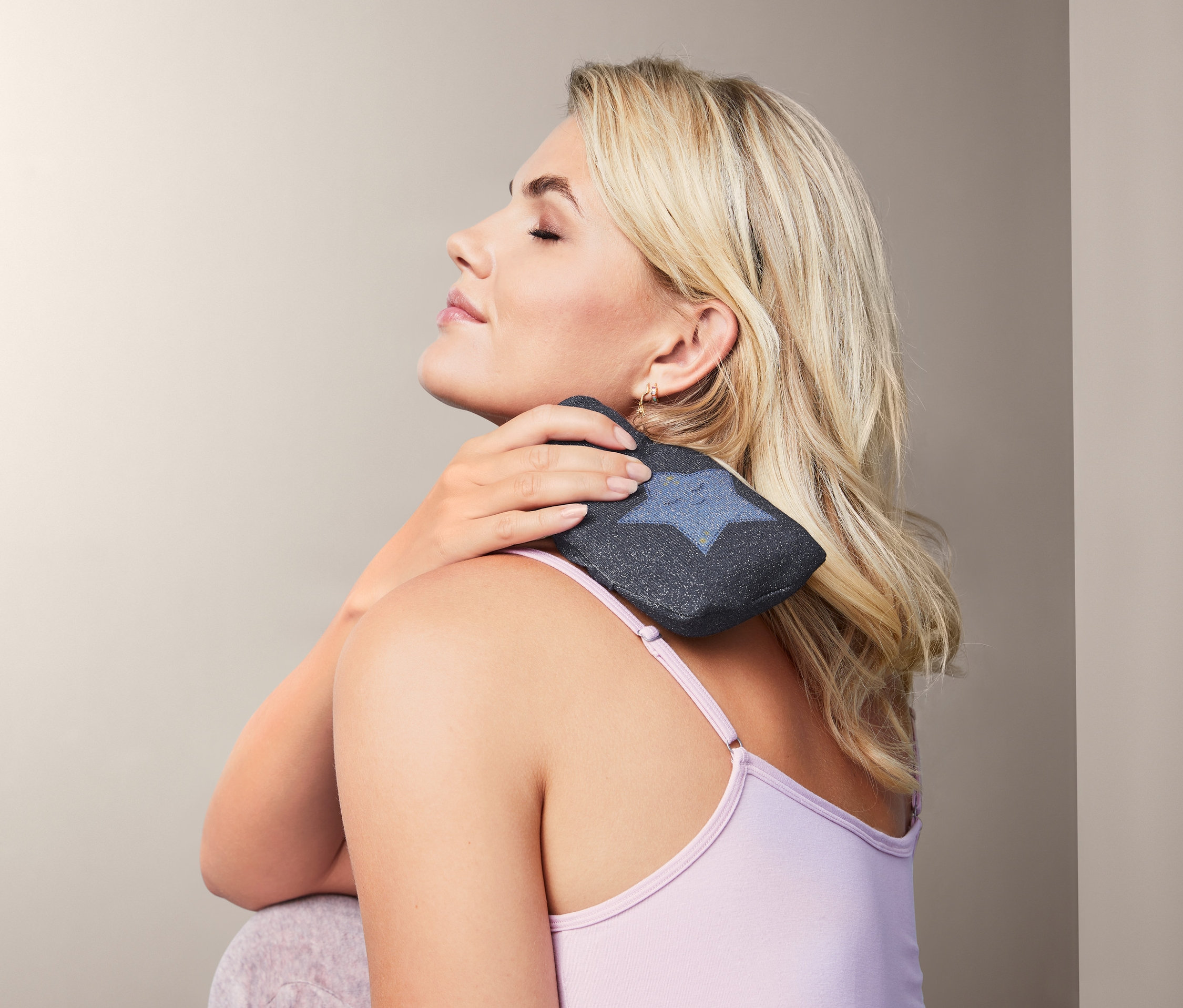 Blondynka trzyma mini termofor na szyi.