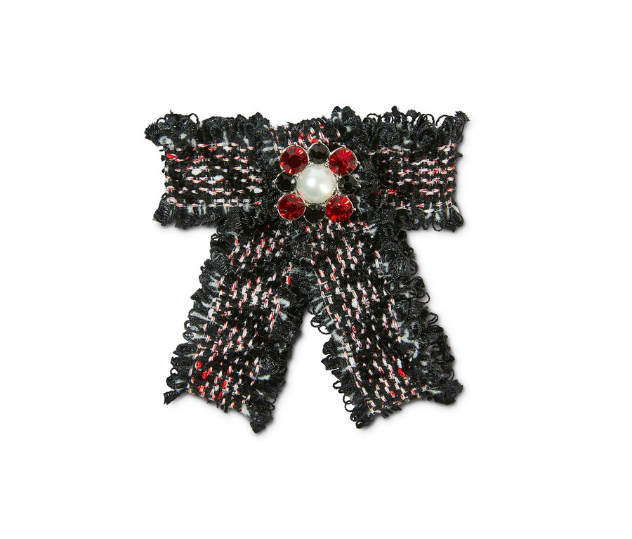 Zbliżenie na broszkę w kształcie kokardki z tweedu.