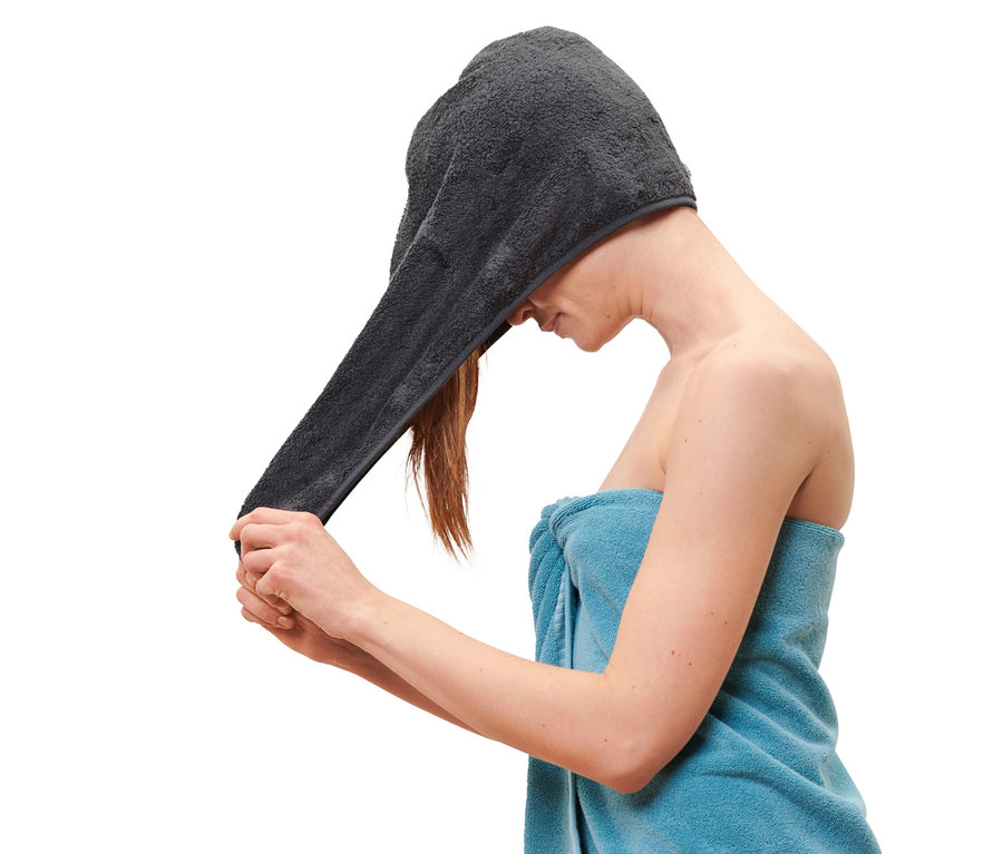 Kobieta zakłada na głowę antracytowy ręcznik-turban.
