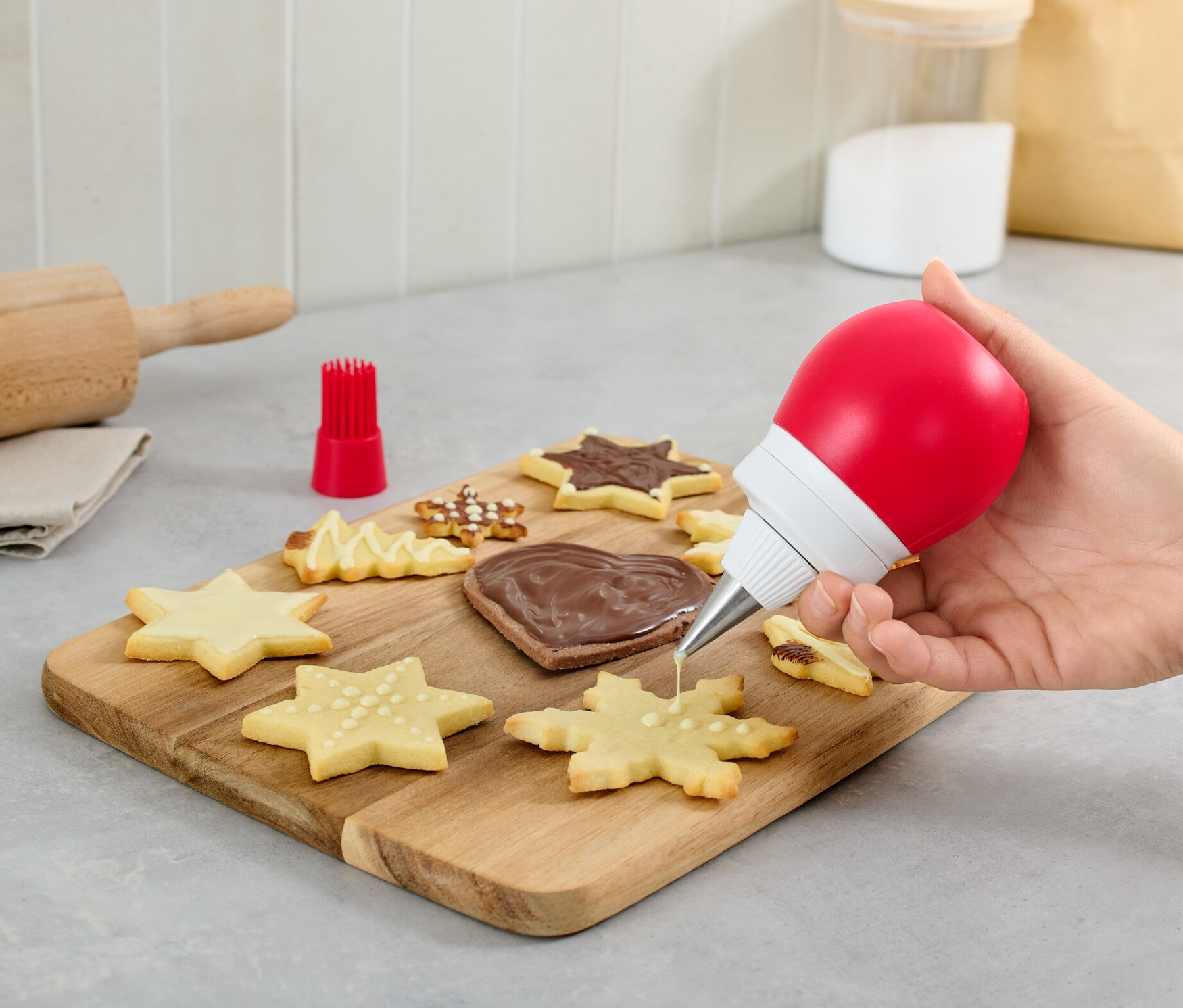 Ręka dekoruje ciastko za pomocą dozownika do dekoracji 2 w 1.