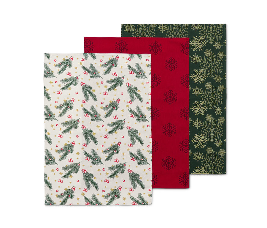 Trzy ścierki do naczyń: jedna z motywem gałązek jodły, druga czerwona z płatkami śniegu, trzecia zielona ze złotymi płatkami śniegu.