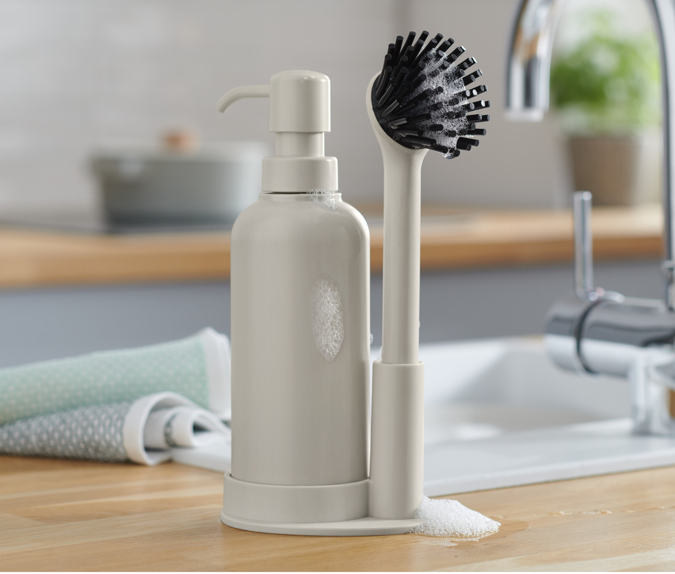 Zestaw do mycia naczyń z dozownikiem i szczotką na blacie.
