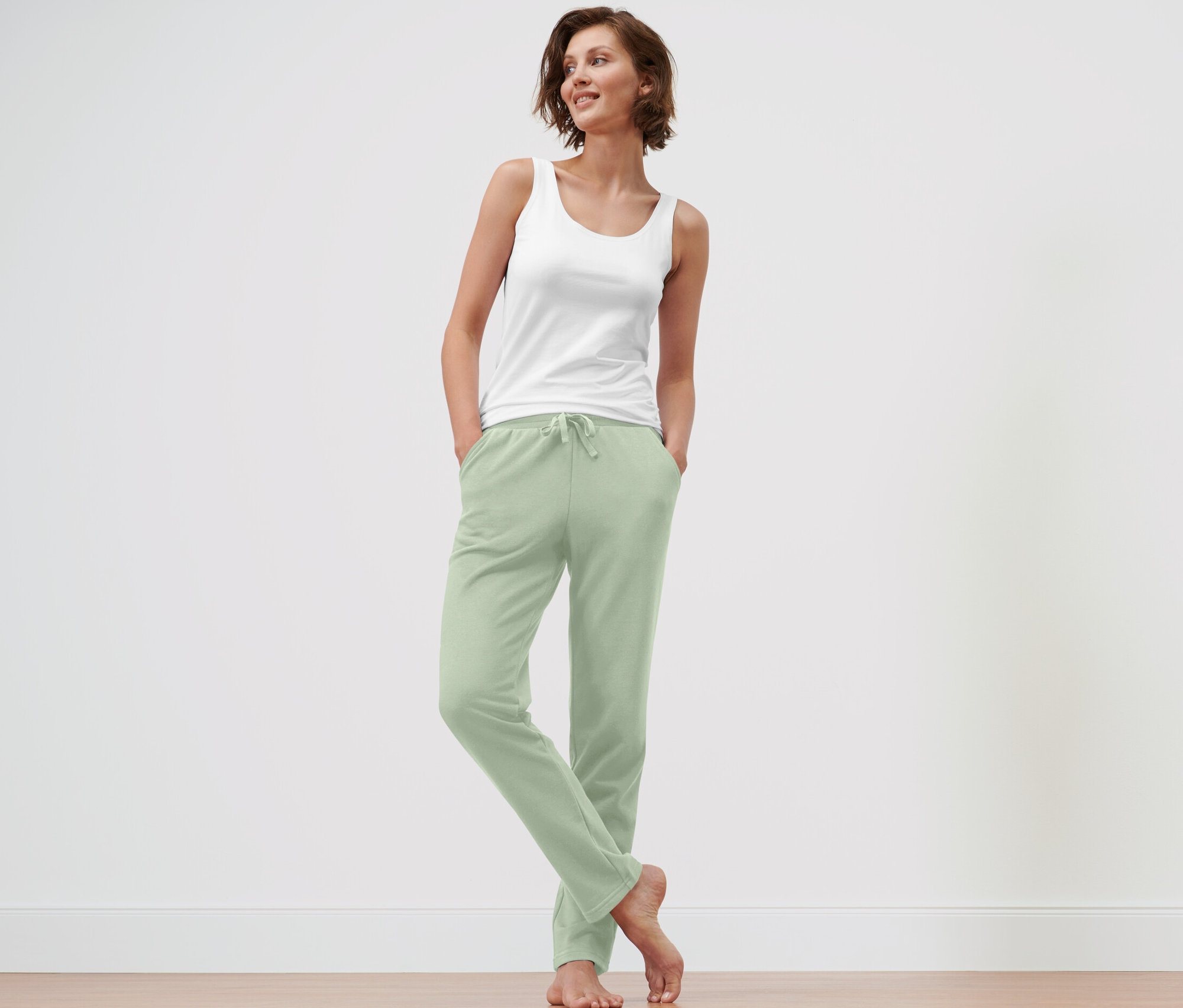 Kobieta stoi z rękami w kieszeniach jasnozielonych spodni Spodnie rekreacyjne.