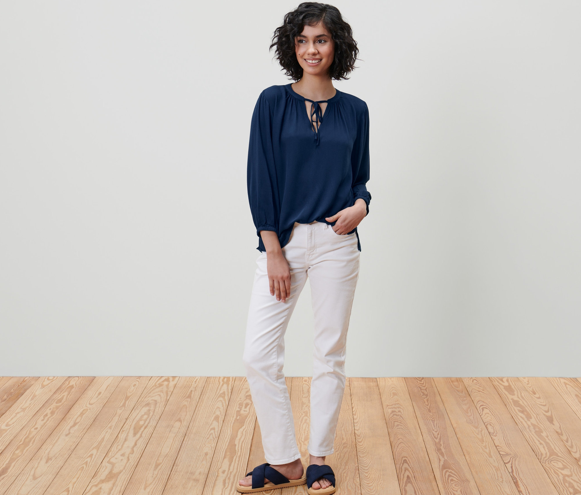 Kobieta stoi i ma na sobie niebieską bluzkę-tunikę.