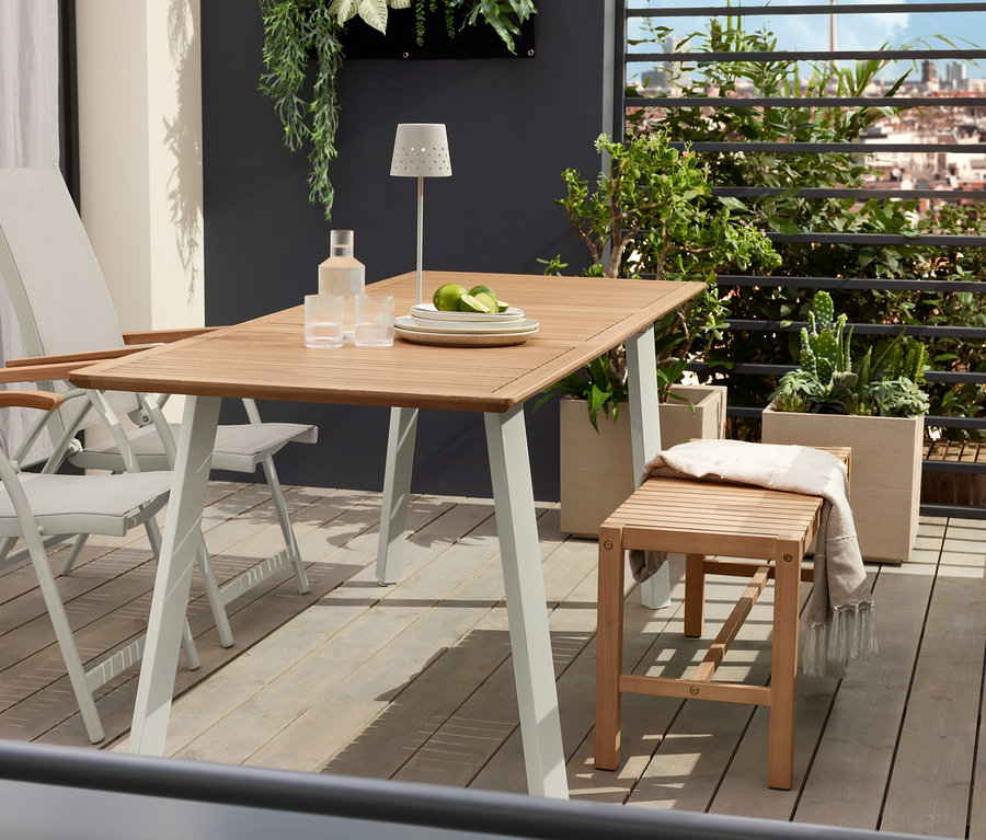 Dwa krzesła z wysokim oparciem »Liska« stoją przy wąskim stole rozsuwanym »Liska«. Na stole stoją dwie metalowe lampy stołowe LED z możliwością ładowania.