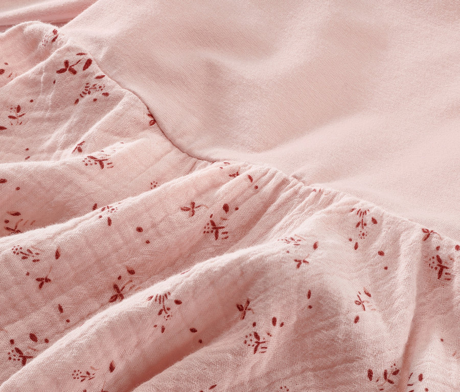 Zbliżenie na różową sukienkę niemowlęcą z tkaniny w kwiatowy wzór.