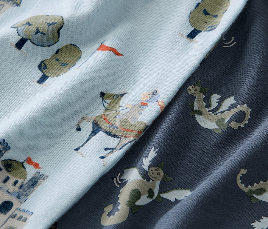 Zbliżenie na niebieską piżamę dziecięcą we wzór rycerza na koniu i zamku.