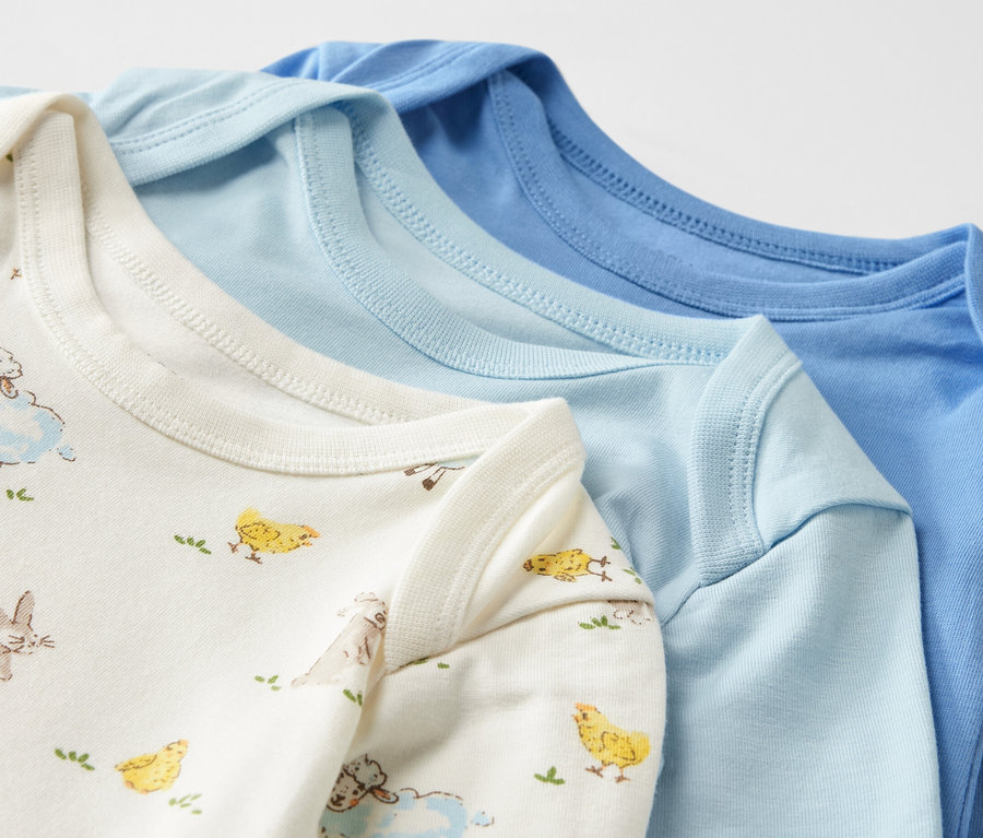 Zbliżenie na trzy niebieskie body niemowlęce rosnące z dzieckiem.