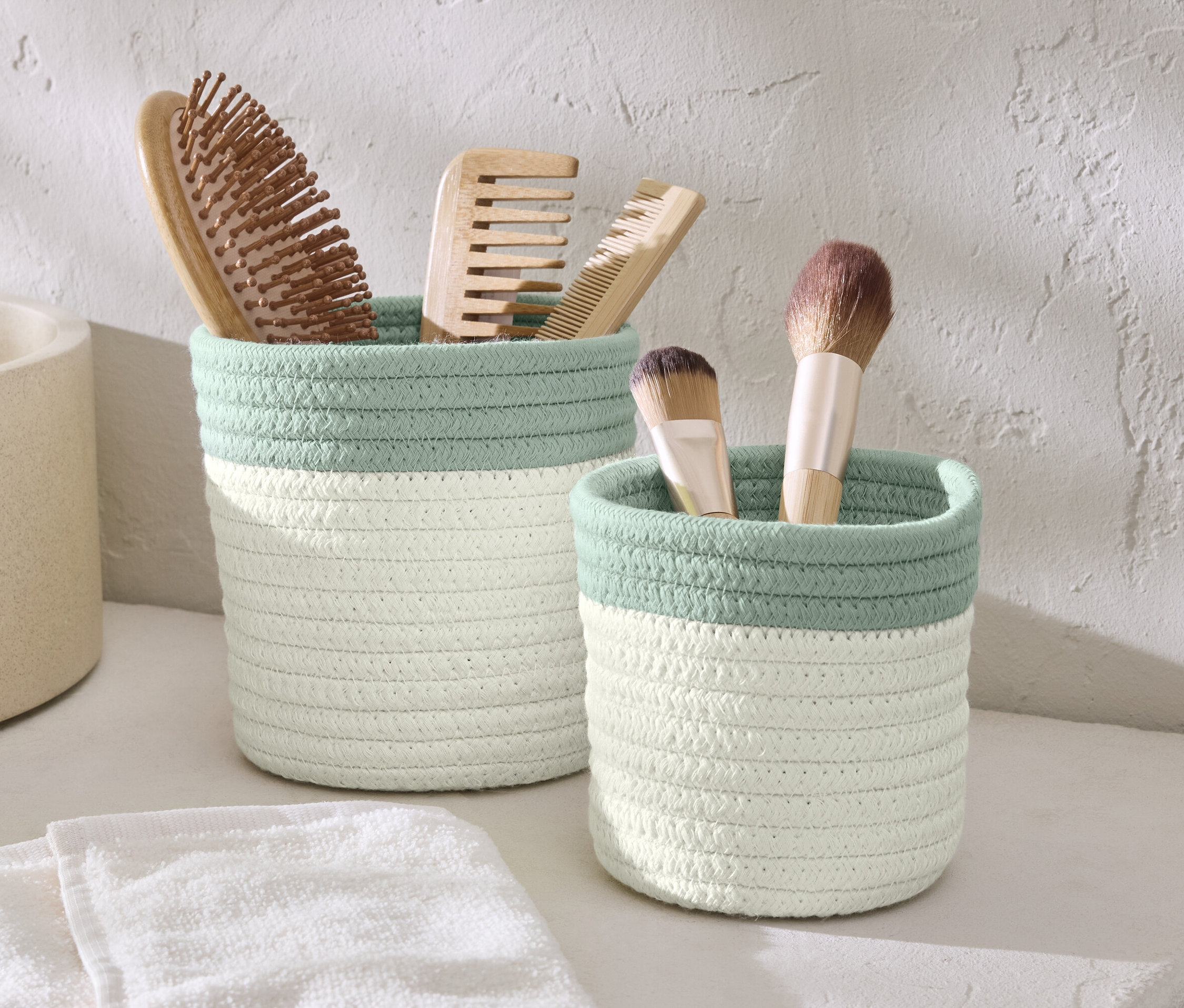 Dwa koszyki do przechowywania ze szczotkami i pędzlami do makijażu.