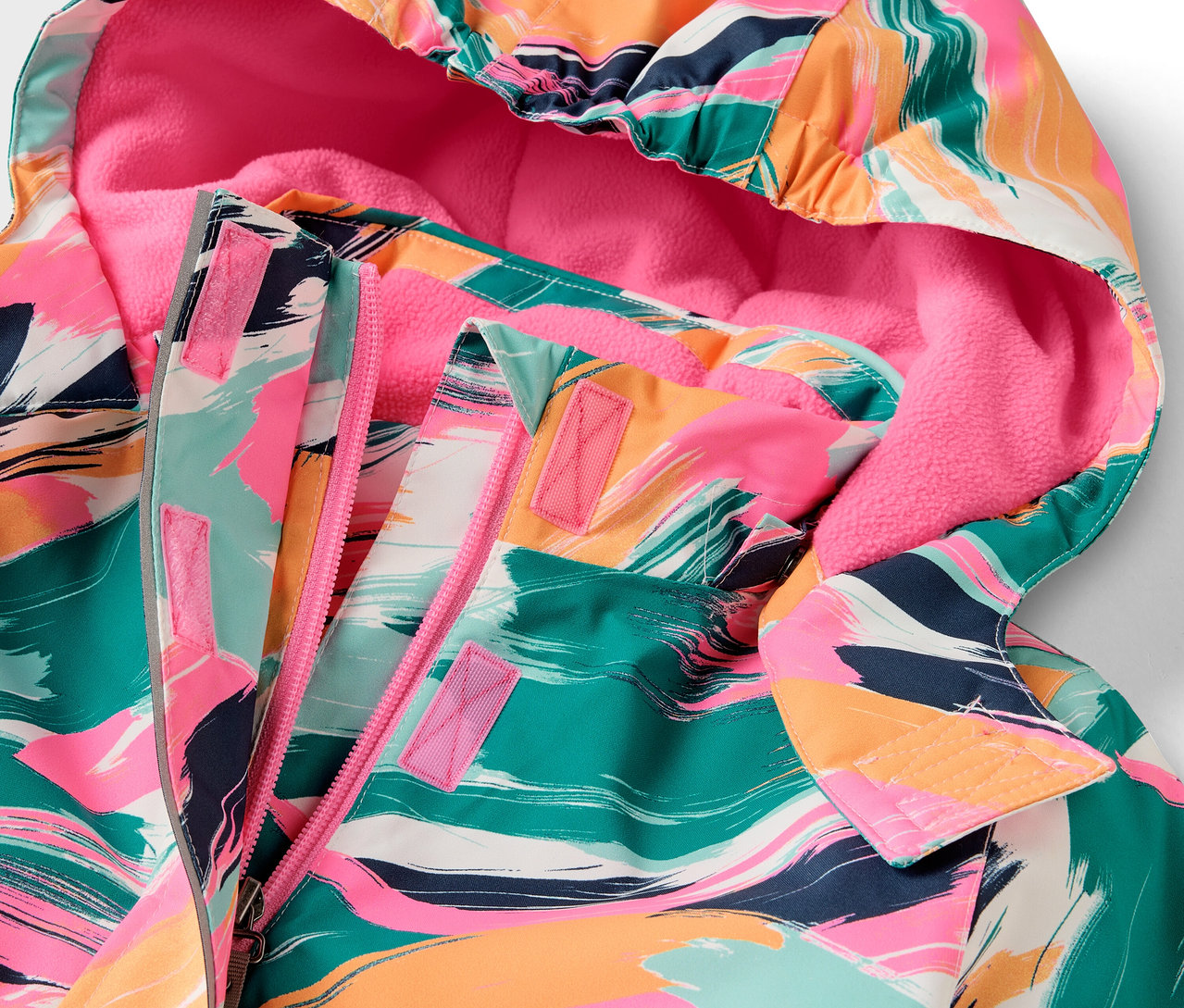 Szczegół kurtki z kapturem o kolorowym wzorze i różowej podszewce.