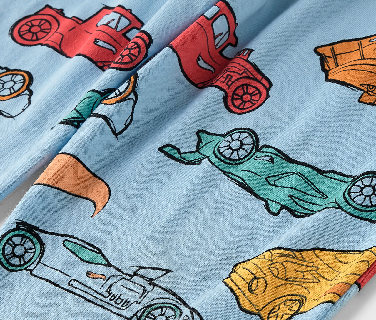 Jasnoniebieska tkanina z nadrukiem kolorowych samochodów.