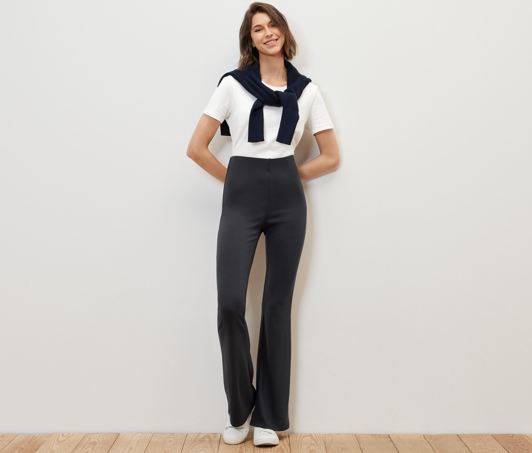 Kobieta stoi i pozuje w rozszerzanych legginsach.