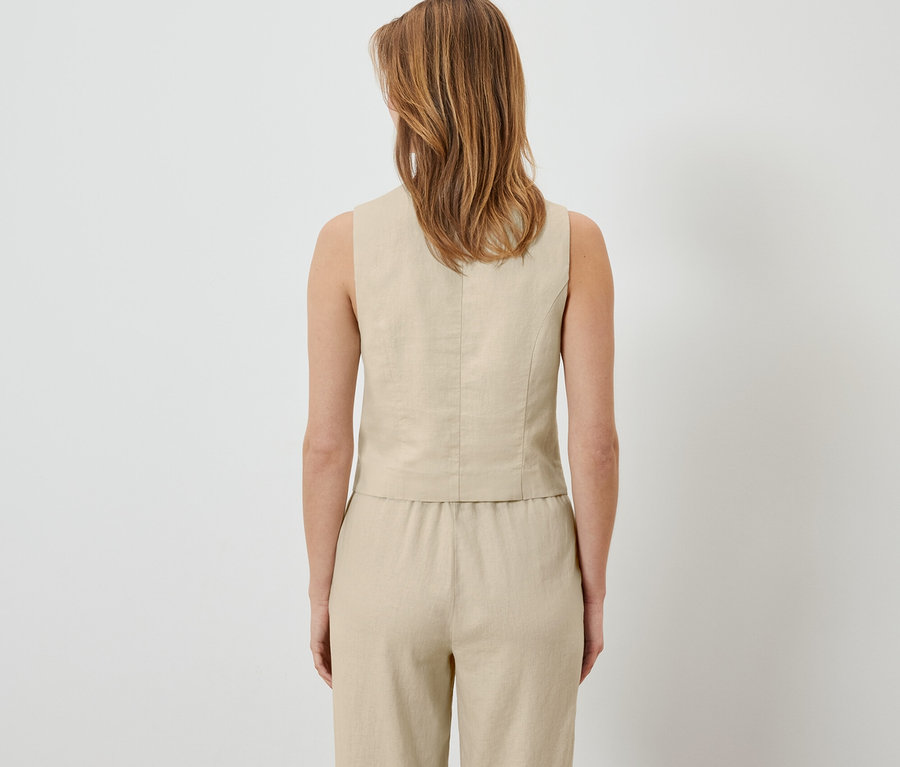Widok z tyłu kobiety w lnianej kamizelce i spodniach.