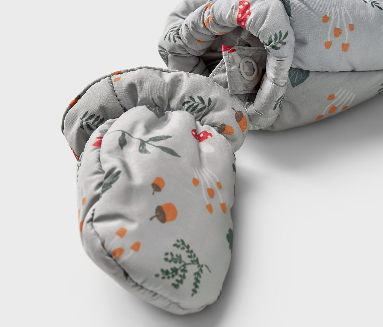 Zbliżenie na niemowlęcy kombinezon zimowy z nadrukiem grzybów, żołędzi i gałązek.