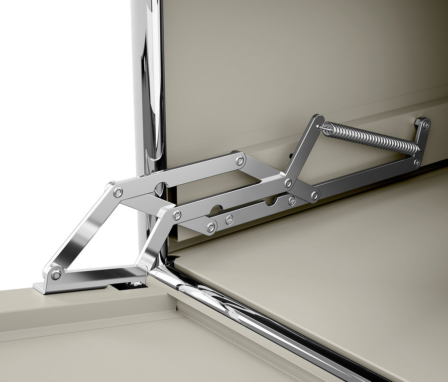 Szczegół chromowanego mechanizmu zawiasu ze sprężyną przy beżowych drzwiach szafki.