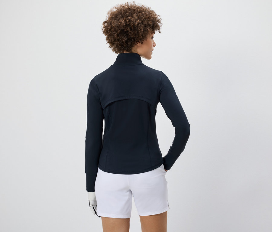 Kobieta ma na sobie bluzę funkcyjną i białe szorty.