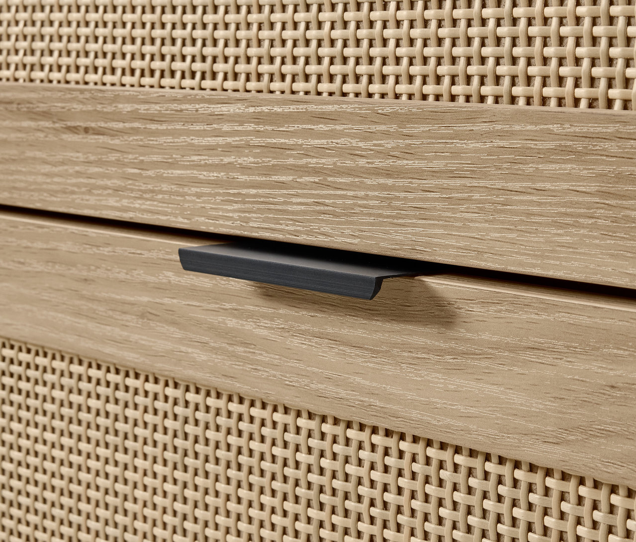 Fragment komody z drewnianą szufladą i plecionym frontem.