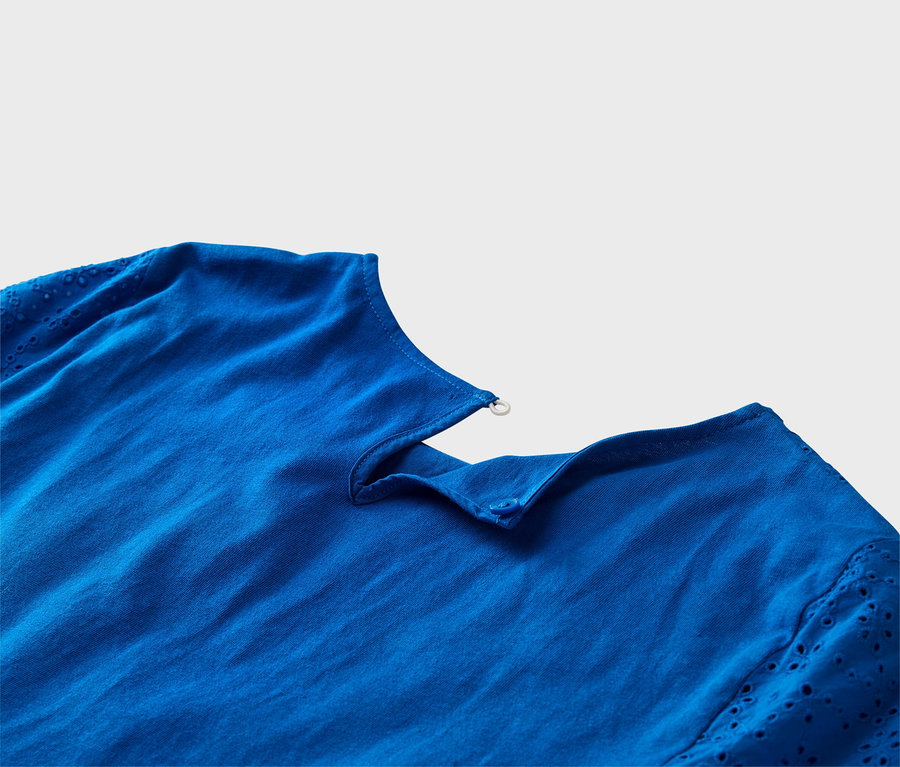 Zbliżenie kobaltowoniebieskiej bluzki z rękawami z haftem dziurkowanym i detalami z guzikami.