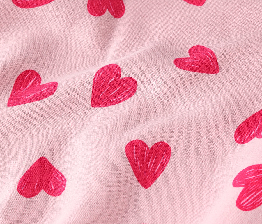 Zbliżenie jasnoróżowej tkaniny w czerwone serduszka.