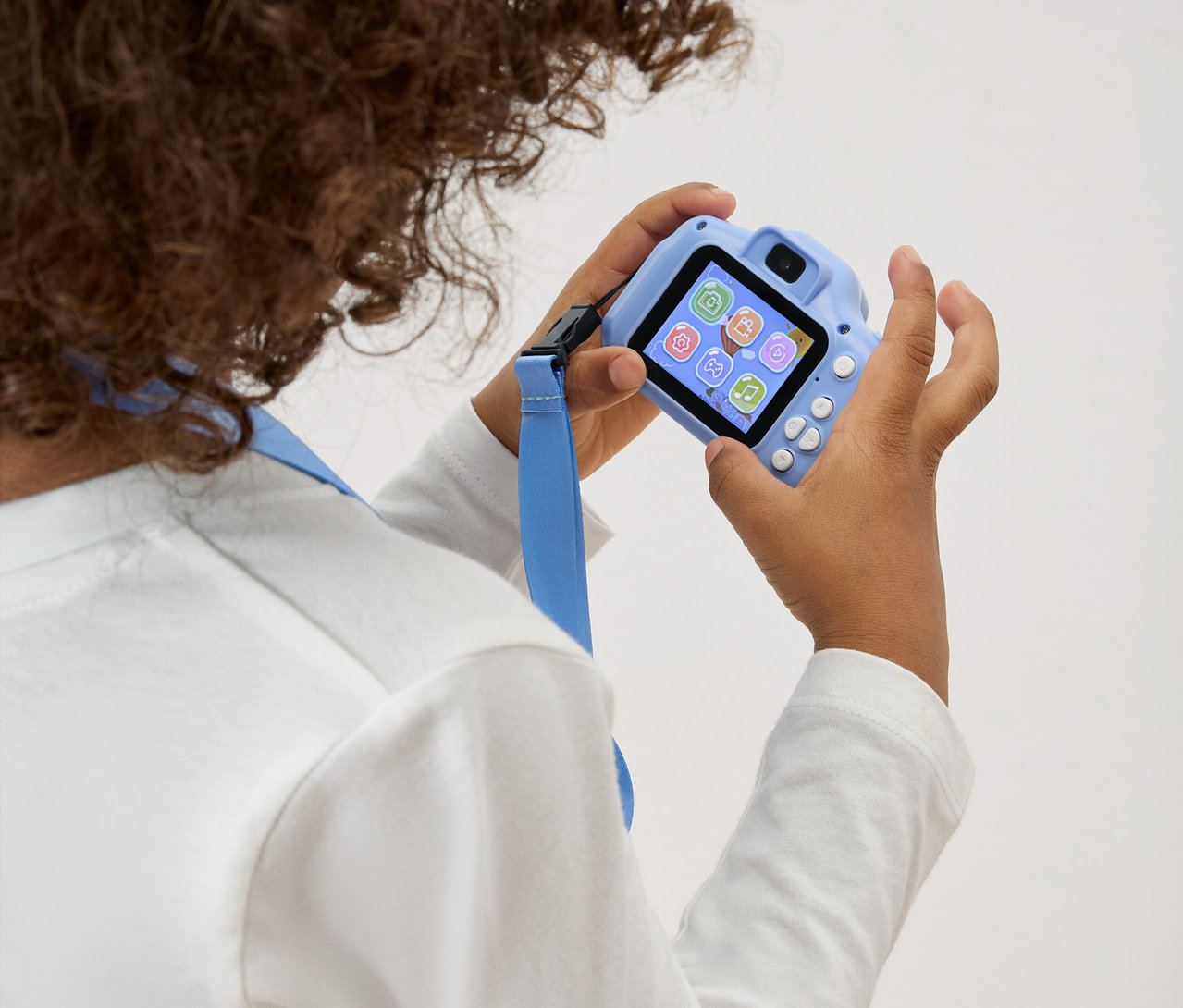 Dziecko trzyma przed sobą jasnoniebieski aparat zabawkowy z niebieskim paskiem.